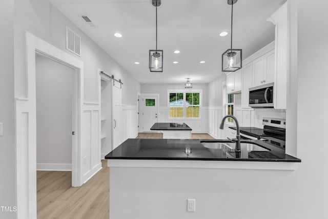 405 N Raiford St, Selma, NC 27576 - kitchen featuring appliances with stainless steel finishes, a sink, white cabinetry, dark countertops, and a barn door