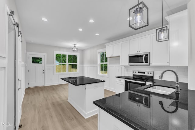 405 N Raiford St, Selma, NC 27576 - kitchen featuring appliances with stainless steel finishes, a sink, light wood finished floors, a center island, and a wainscoted wall