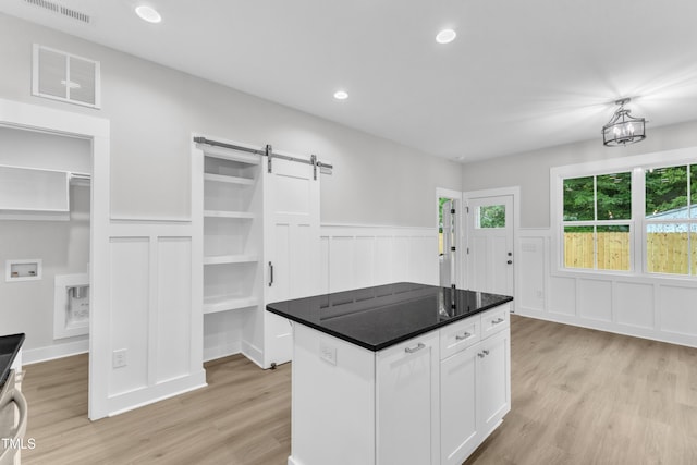405 N Raiford St, Selma, NC 27576 - kitchen featuring a decorative wall, a barn door, light wood finished floors, a wainscoted wall, and white cabinets