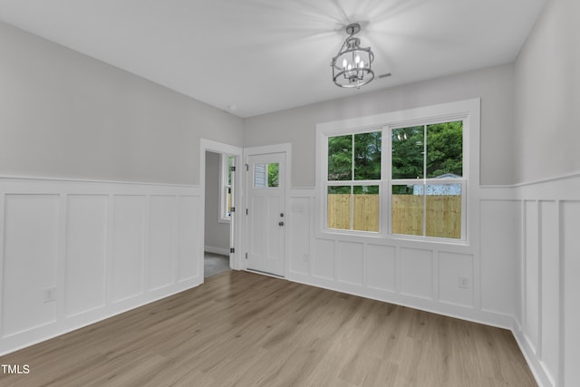 405 N Raiford St, Selma, NC 27576 - foyer entrance featuring a decorative wall, a chandelier, light wood-type flooring, a wainscoted wall, and healthy amount of natural light