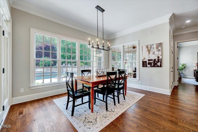 dining space featuring crown molding, a notable chandelier, baseboards, visible vents, and dark wood-style floors
