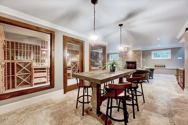 dining area featuring baseboards, a stone fireplace, and ornamental molding