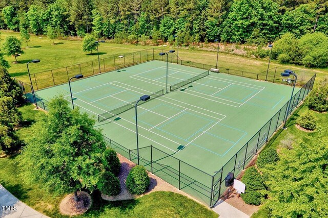 view of sport court with fence and a lawn