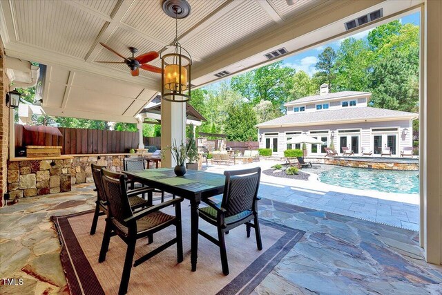view of patio / terrace with a storage structure, fence, outdoor dining area, french doors, and an outbuilding