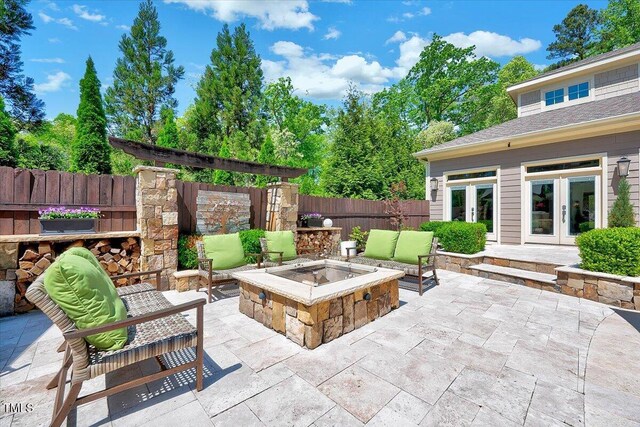 view of patio with a fire pit, fence, and french doors