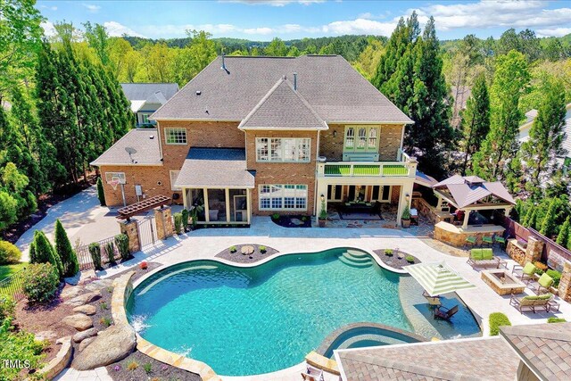 view of swimming pool featuring a patio, a fenced backyard, an outdoor hot tub, a fenced in pool, and a forest view