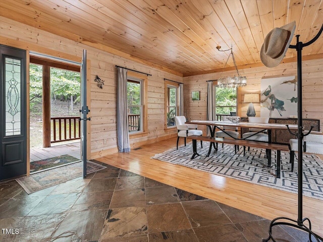 dining space with plenty of natural light, stone tile floors, wood ceiling, and wooden walls