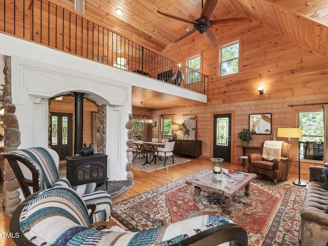 living room featuring plenty of natural light, a wood stove, high vaulted ceiling, and wooden ceiling