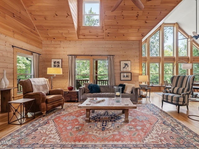living area with a ceiling fan, wood finished floors, wooden walls, and high vaulted ceiling