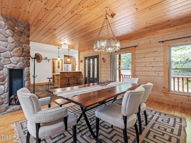 dining room featuring wood ceiling, french doors, wood walls, wood finished floors, and a chandelier