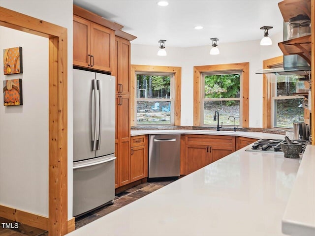 kitchen with a sink, light countertops, stainless steel appliances, and brown cabinets
