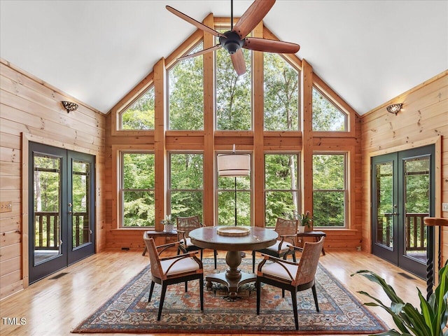 sunroom with french doors, wood walls, and high vaulted ceiling