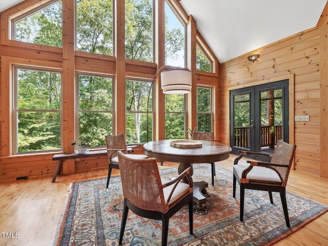sunroom with wooden walls, high vaulted ceiling, french doors, and wood finished floors