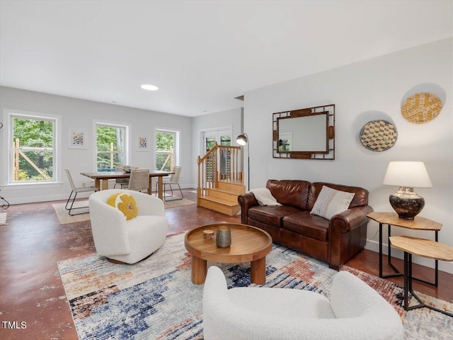 living room featuring baseboards, a wealth of natural light, and finished concrete flooring