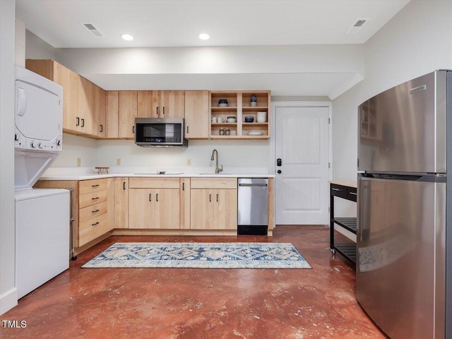 kitchen with light brown cabinetry, stacked washer and dryer, appliances with stainless steel finishes, finished concrete flooring, and visible vents