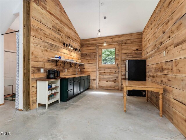 bar featuring decorative light fixtures, wood walls, a sink, concrete floors, and lofted ceiling