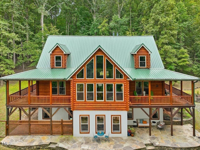 rear view of property featuring log exterior, a patio area, and metal roof