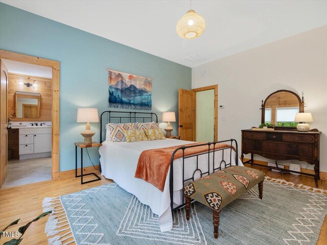 bedroom featuring baseboards, wood finished floors, and connected bathroom
