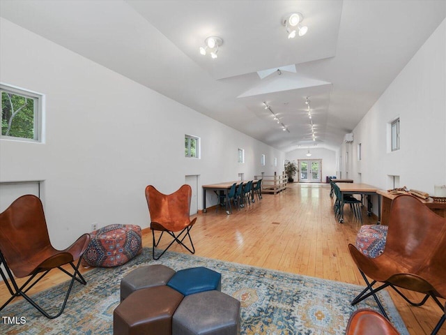 living area featuring baseboards, lofted ceiling, and hardwood / wood-style flooring