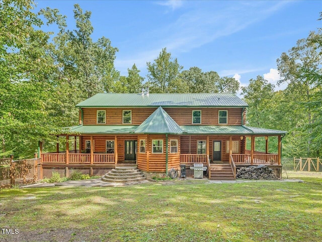 rear view of property with a lawn, fence, a porch, and metal roof