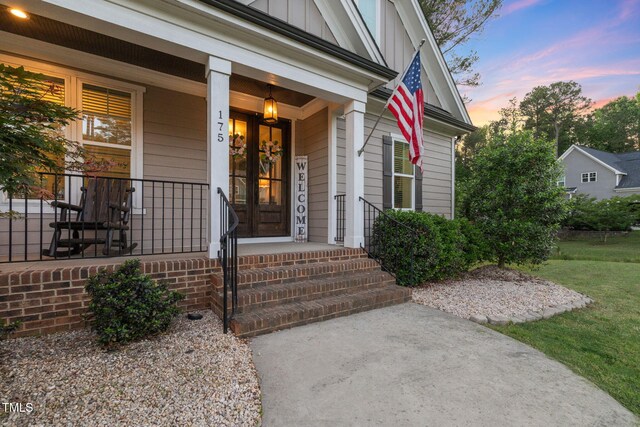 175 Lockamy Ln, Youngsville, NC 27596 - view of exterior entry with board and batten siding, a lawn, and a porch