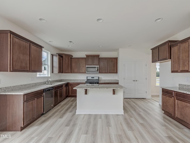 kitchen featuring a wealth of natural light, stainless steel appliances, light wood finished floors, and a sink