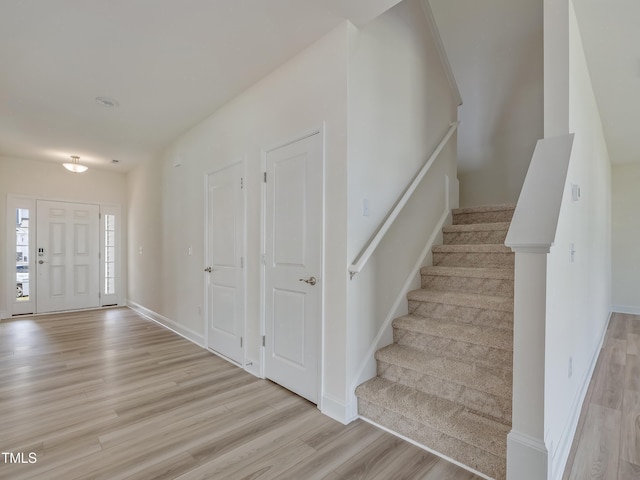 foyer featuring baseboards, stairs, and light wood-style floors