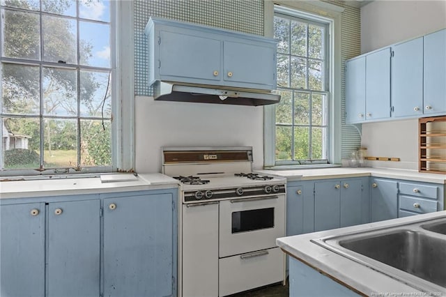 205 N Vance St, Pembroke, NC 28377 - kitchen featuring light countertops, blue cabinetry, under cabinet range hood, and gas range gas stove