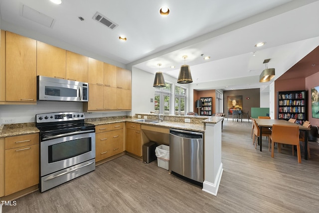 kitchen featuring a sink, visible vents, stainless steel appliances, light wood-style floors, and a peninsula