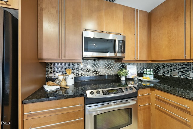 kitchen with dark stone countertops, brown cabinets, stainless steel appliances, and tasteful backsplash