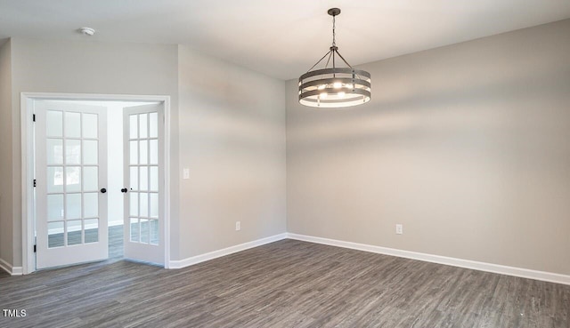 empty room with a chandelier, french doors, dark wood-style floors, and baseboards