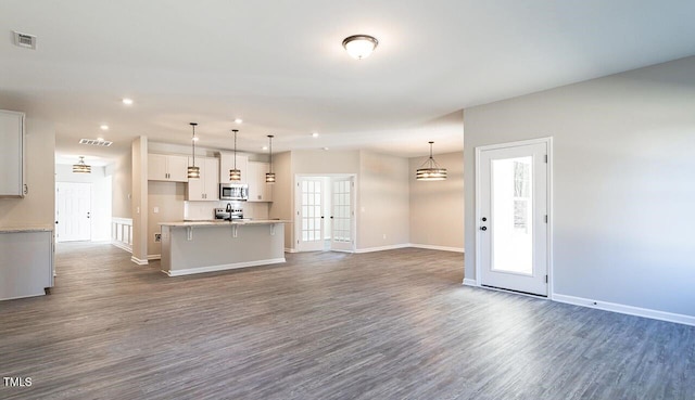 kitchen featuring dark wood-style floors, visible vents, open floor plan, and stainless steel microwave