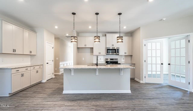 kitchen featuring appliances with stainless steel finishes, baseboards, dark wood finished floors, and a sink