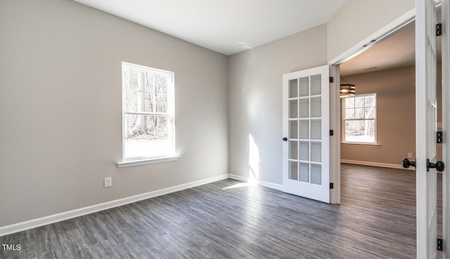 empty room with dark wood-style floors, baseboards, a chandelier, and french doors
