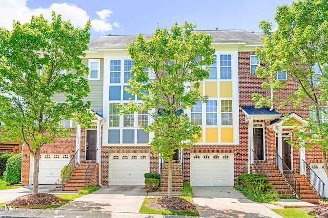 multi unit property with driveway, an attached garage, and brick siding