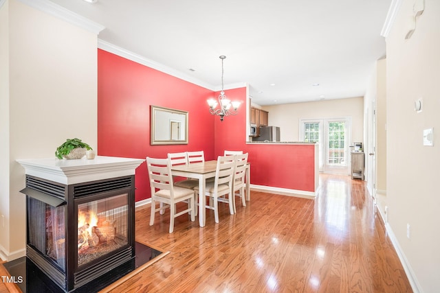 dining room with light wood-type flooring, baseboards, a chandelier, and ornamental molding
