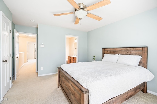 bedroom with light colored carpet, baseboards, ceiling fan, and ensuite bath