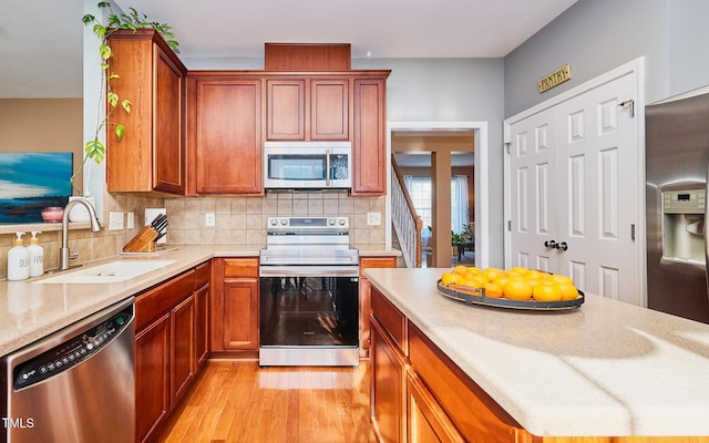 5031 Mckittrick Ln, Durham, NC 27712 - kitchen featuring appliances with stainless steel finishes, light wood-style flooring, tasteful backsplash, and brown cabinetry