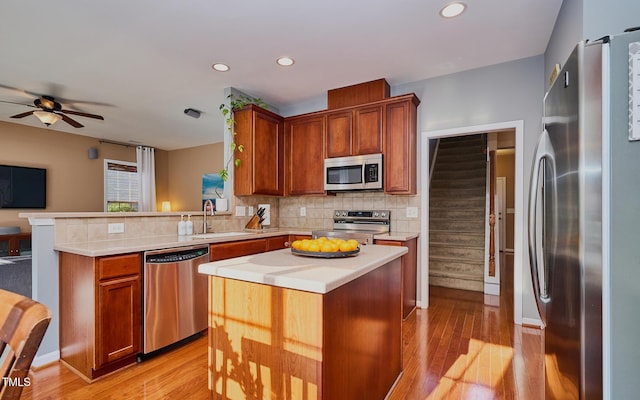 5031 Mckittrick Ln, Durham, NC 27712 - kitchen with appliances with stainless steel finishes, a peninsula, light countertops, light wood-style flooring, and recessed lighting