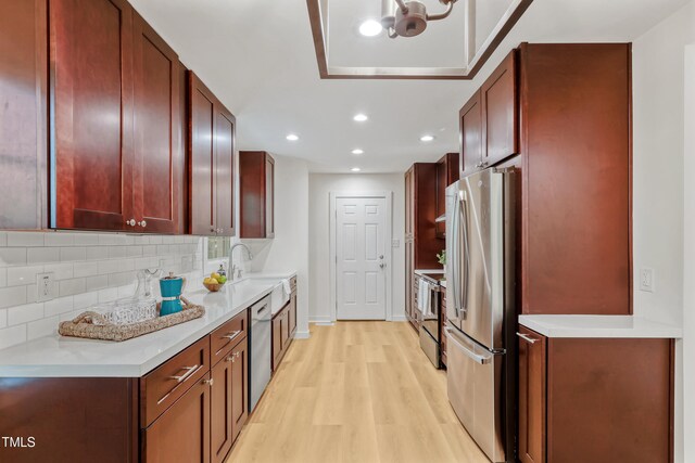 2311 Wintergreen Pl, Durham, NC 27707 - kitchen with dark brown cabinets, stainless steel appliances, baseboards, light wood-type flooring, and tasteful backsplash