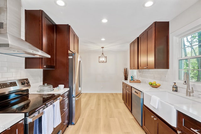 2311 Wintergreen Pl, Durham, NC 27707 - kitchen featuring light wood-style floors, wall chimney range hood, light countertops, a sink, and appliances with stainless steel finishes