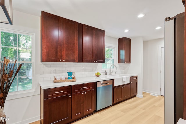 2311 Wintergreen Pl, Durham, NC 27707 - kitchen featuring stainless steel dishwasher, decorative backsplash, a wealth of natural light, and light wood finished floors
