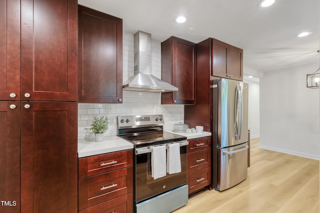 2311 Wintergreen Pl, Durham, NC 27707 - kitchen featuring appliances with stainless steel finishes, light wood-type flooring, light countertops, reddish brown cabinets, and wall chimney exhaust hood