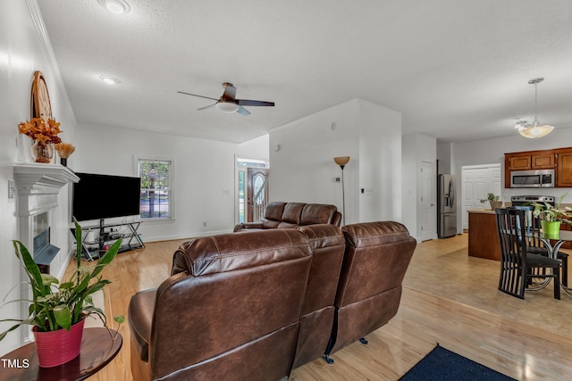 living area featuring ceiling fan, light wood-style floors, a fireplace, and baseboards