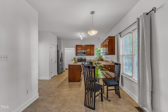kitchen with appliances with stainless steel finishes, baseboards, plenty of natural light, and light countertops