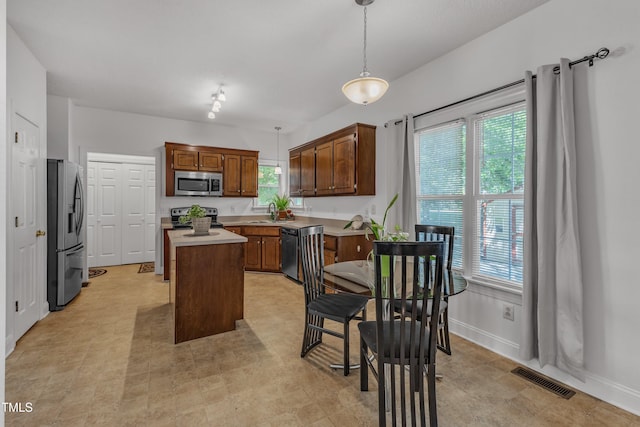 kitchen with stainless steel appliances, a center island, light countertops, and baseboards