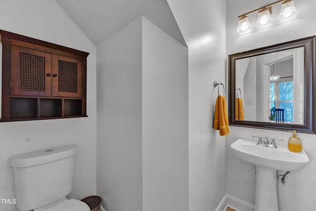 bathroom with lofted ceiling, baseboards, and toilet