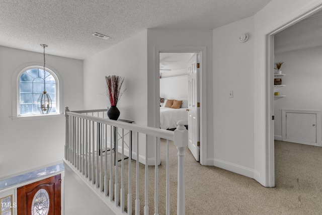 hall featuring carpet, a textured ceiling, and baseboards