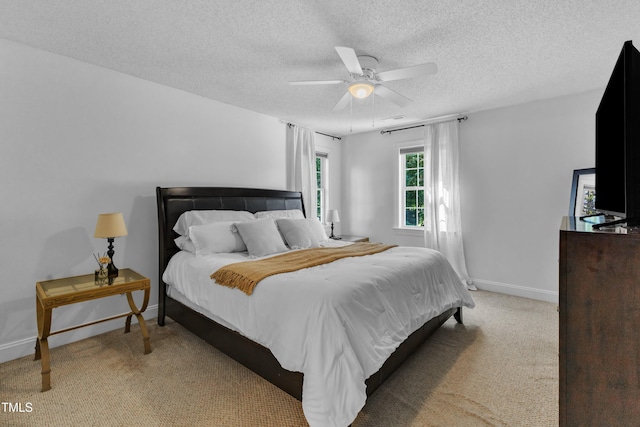 bedroom with light colored carpet, a textured ceiling, baseboards, and ceiling fan