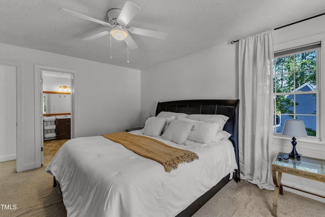 carpeted bedroom featuring a textured ceiling, a ceiling fan, and ensuite bath